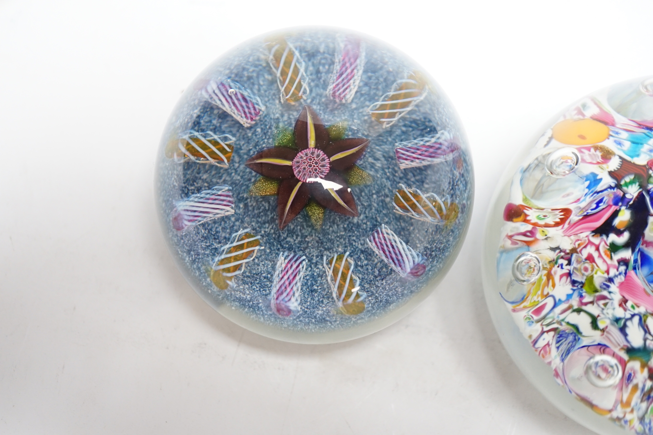 Two Paul Ysart glass paperweights, comprising a purple flower and latticino spoke on a blue jasper ground, ‘H’ cane, PY label, 7cm and ‘Harlequin’ glass paperweight, PY paper label, 8cm